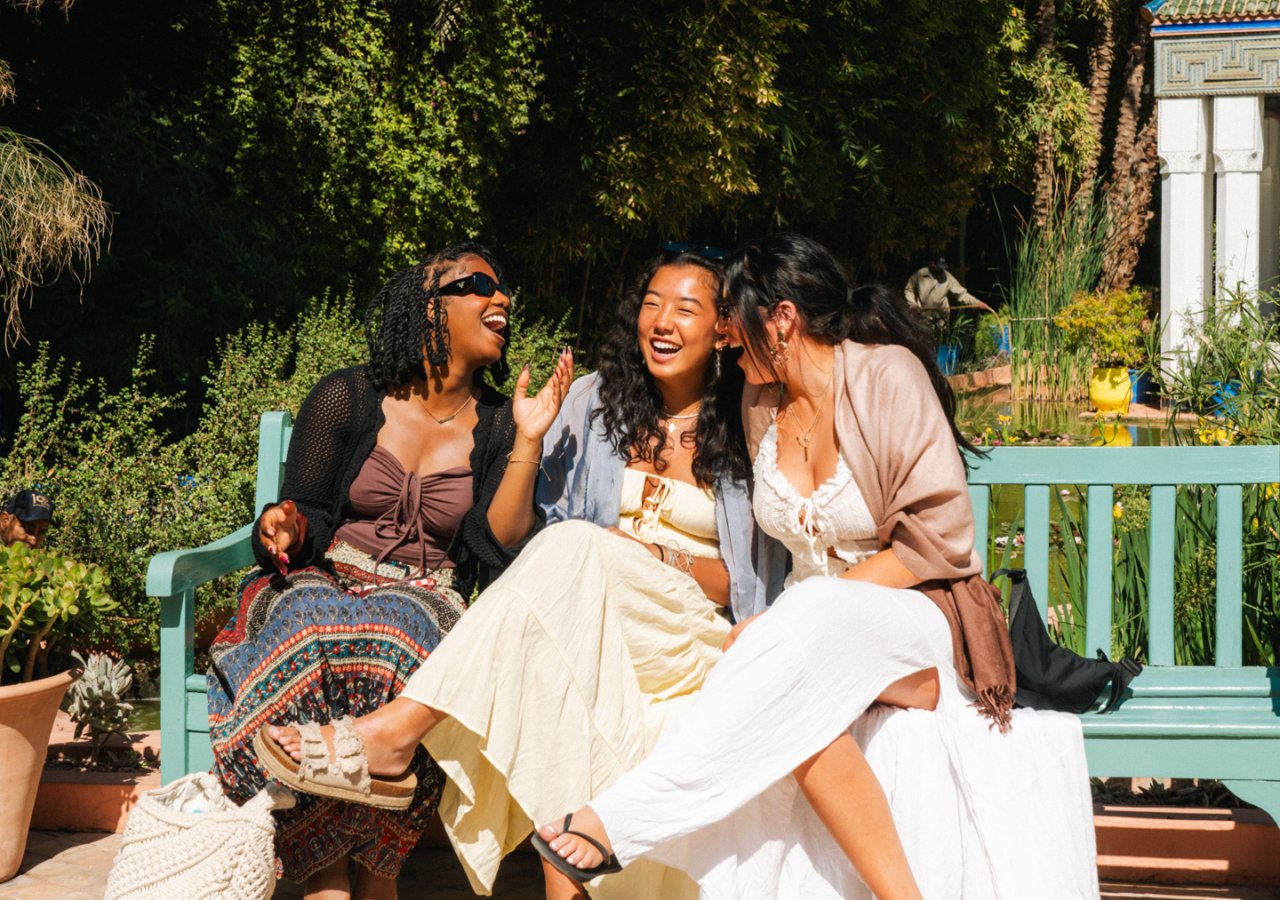 A group of female travellers laugh and bond whilst enjoying the views at Jardin Majorelle in Marrakech Morocco