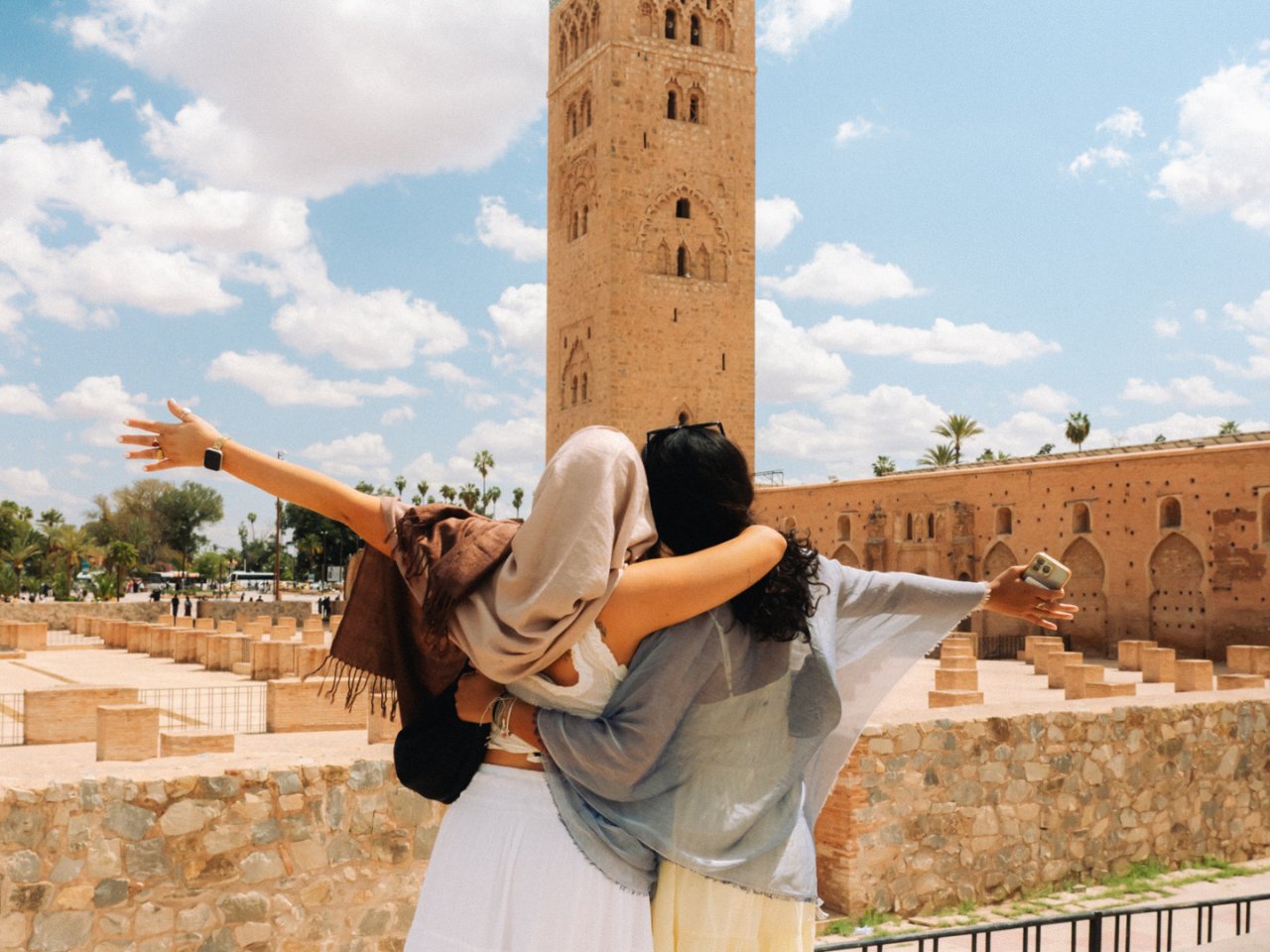 Two young female travellers in Morocco pose in front of Kutubiyya Mosque in Marrakech