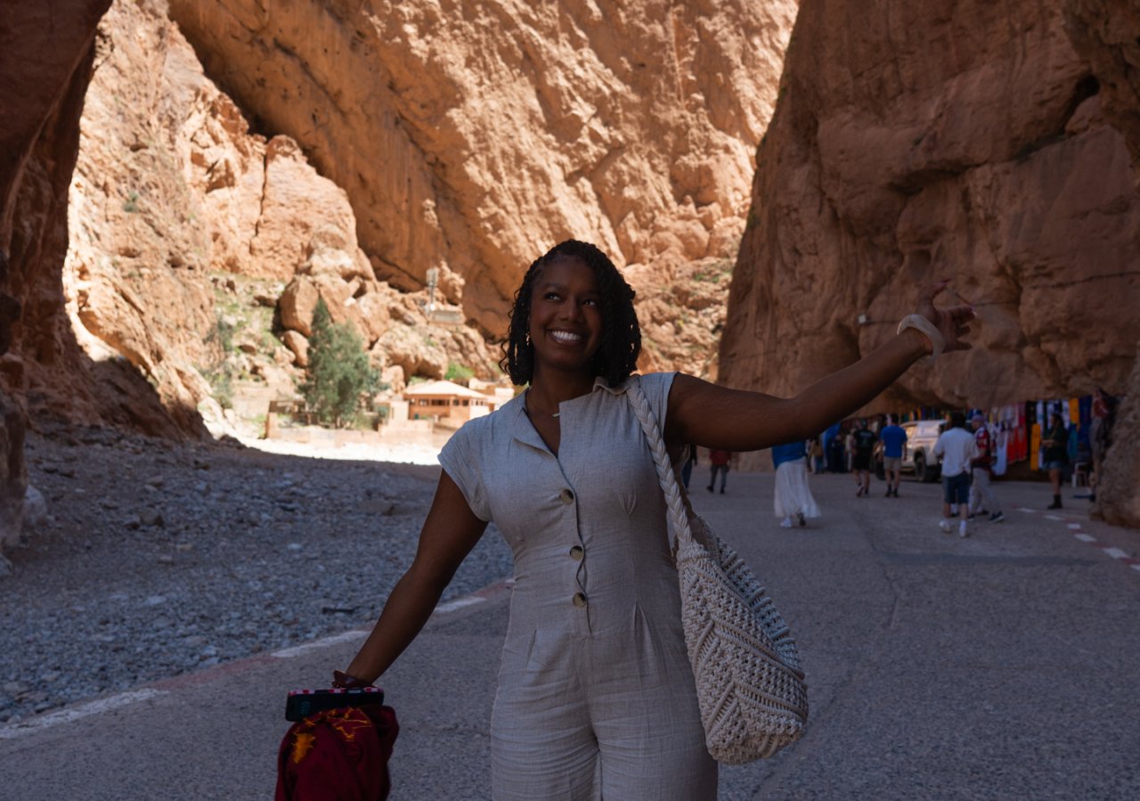 A very happy solo traveller poses with the background of Todra Gorge in Morocco