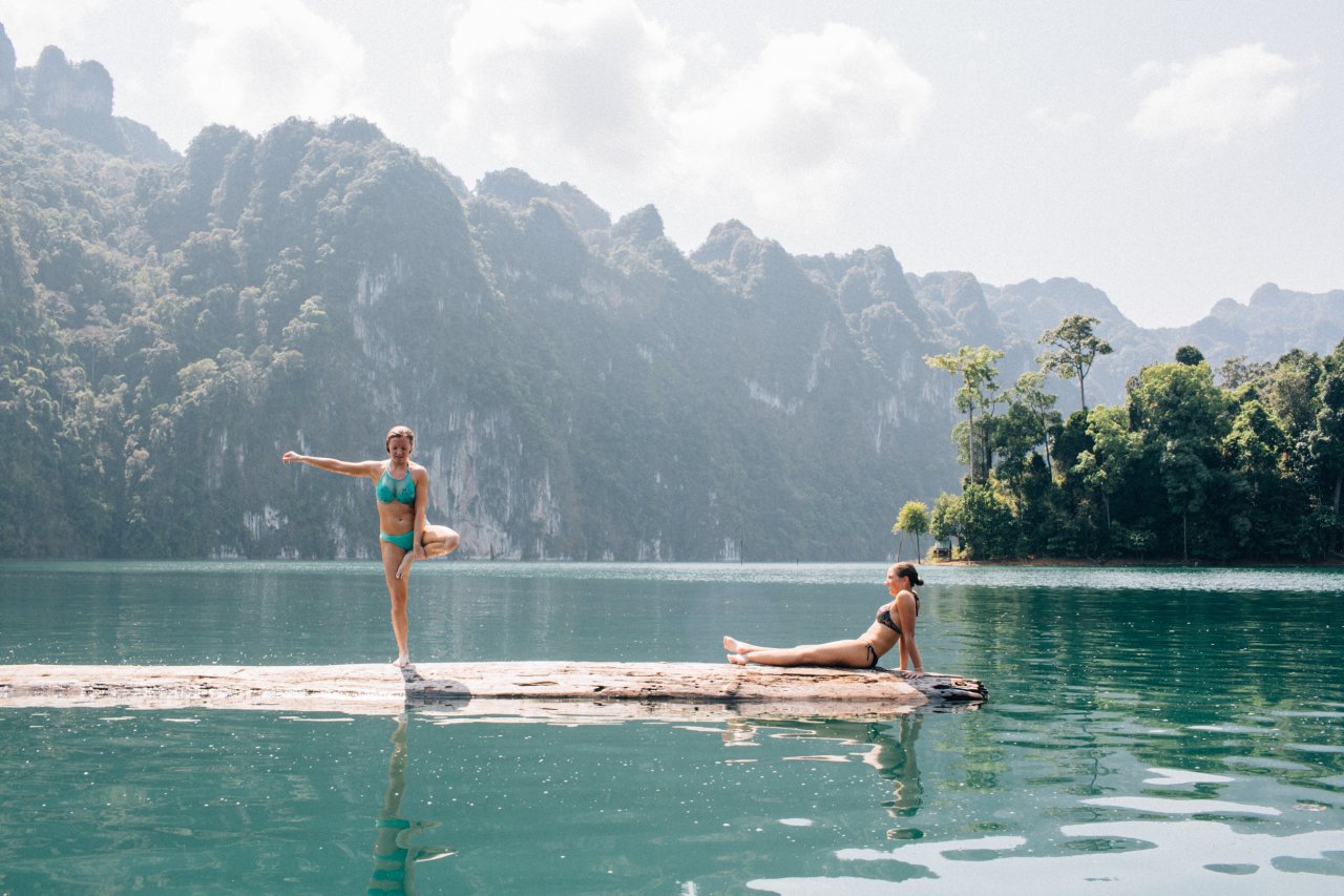Two girls on the log in the middle of the lake at Khao Sok National park in Thailand