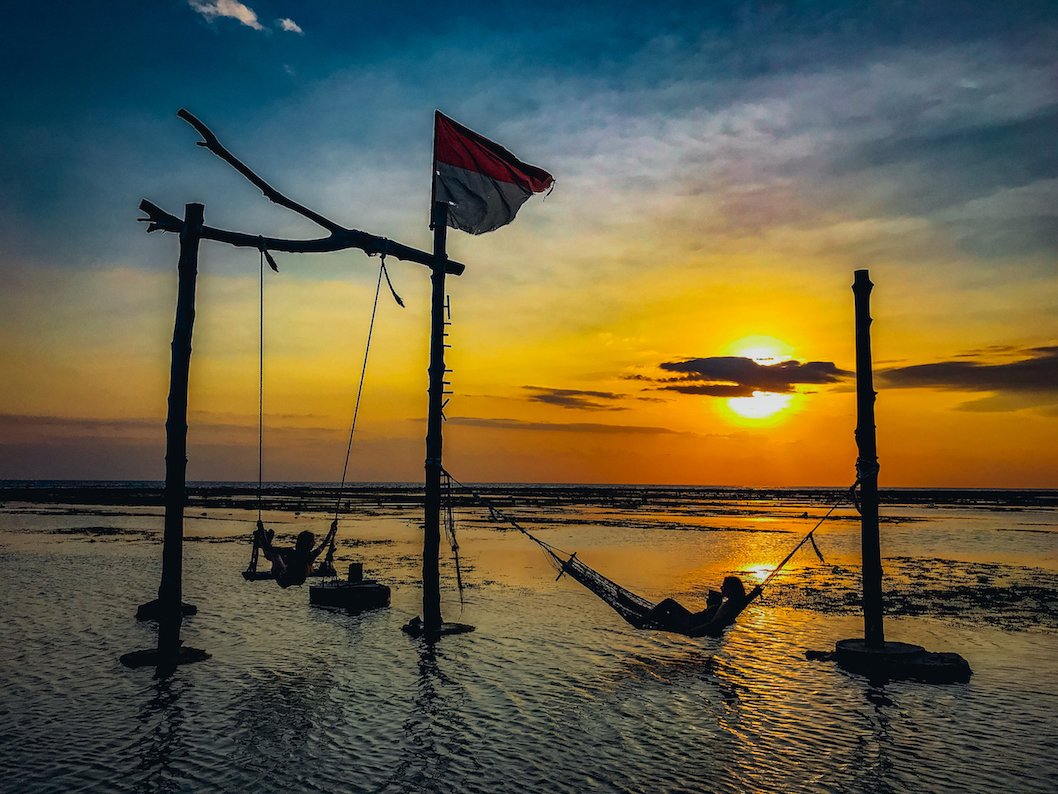 sea swings with orange sunset and girl in hammock 