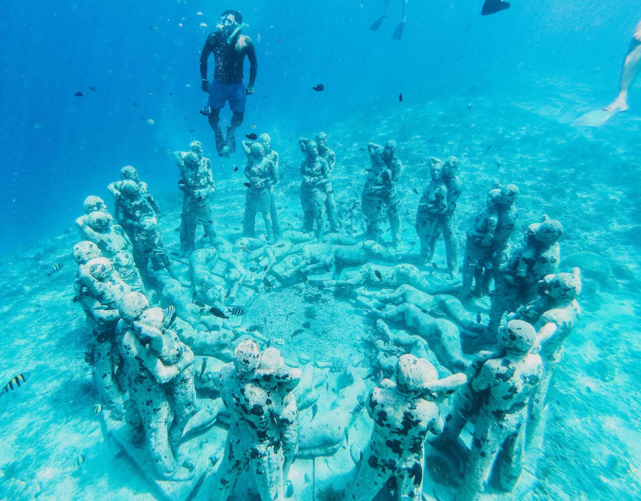 A photo of a man underwater by statues while snorkelling in the bright blue clear sea in Gili Trawangan, Indonesia 