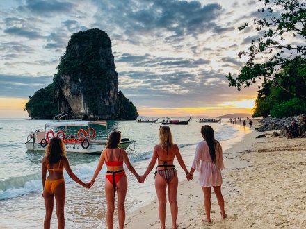 Four girls stood hand in hand at Railay beach, Krabi, Thailand watching the sun set 